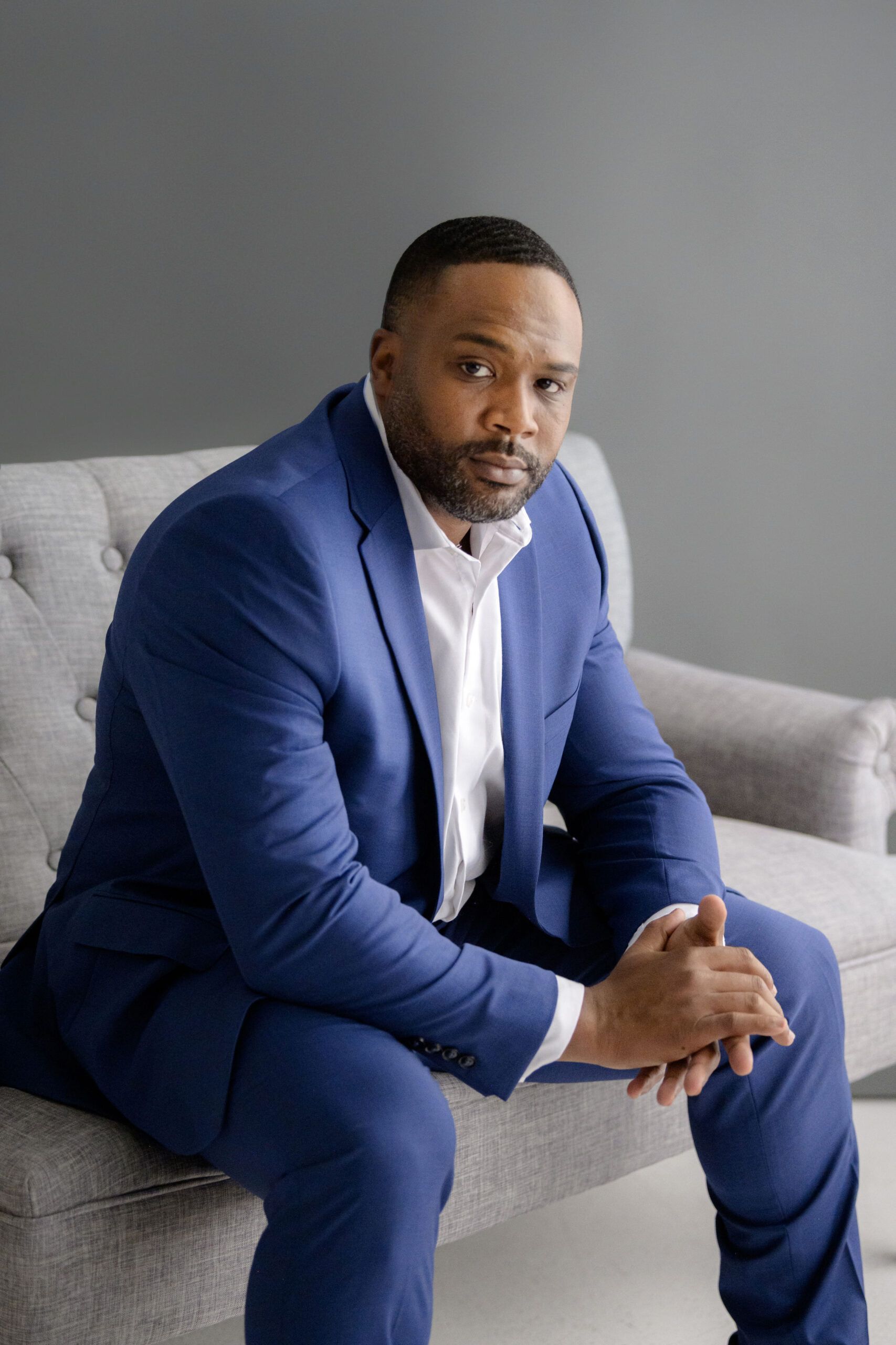 Image of George Bolton seated in a blue suit. 